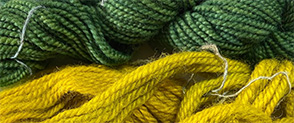 A close up of strands of wool, the top half is green and the bottom half is mustard.