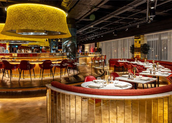 The interior of the Duck & Waffle restaurant in Edinburgh showing curved gold booths with red velvet seating