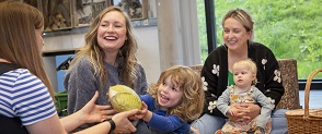 Three adults and two children play with a plastic cabbage. 