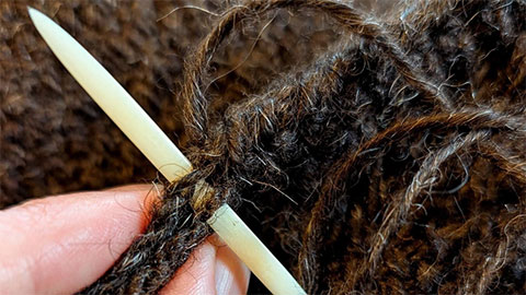 A cream knitting needle in some brown yarn.