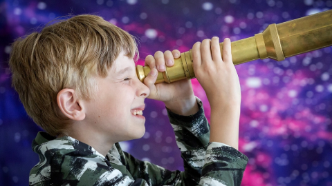 A young boy looks through a telescope.