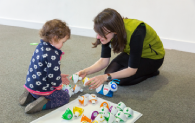 A learning assistant show a young visitor some science related objects.