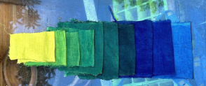 Ten swatches of fabric dyed in bright colours gradiating from yellow to green to blue