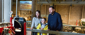 A family of three consisting of a woman, man and a child look at tractors at the National Museum of Rural Life.