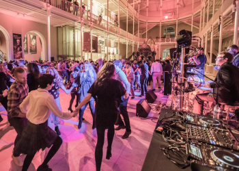A large group of people are dancing as part of a ceilidh in the Grand Gallery 