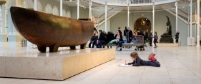 A child lies on the floor of the Grand Gallery drawing a historic object 