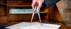 A hand holds a compass on a map. 