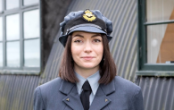 A woman in a blue RAF uniform is looking directly at the camera, outside at the National Museum of Flight.