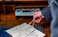 A military officer uses a compass to examine a map. 