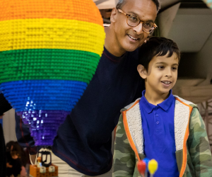 A father and son stand admiring LEGO creations, including a rainbow coloured hot air balloon made from LEGO.