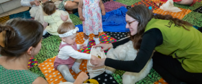 A interpretation assistant plays with a baby, looking at different objects in a fabric bag. 