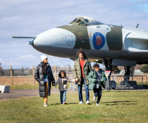 A family of four walk in front a plane at the National Museum of Flight.