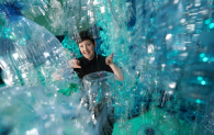 Curator Dr Ali Clark peaks through George Nuku's Bottled Ocean exhibit as part of Rising Tide.