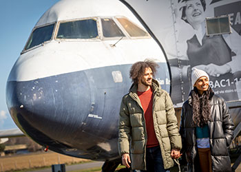 Two visitors wearing warm jackets hold hands while walking in the 