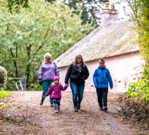 A family of four, two women and two children, walk through the autumnal countryside at the National Museum of Rural Life. 