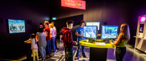 A varied group of visitors are playing games inside Game On at the National Museum of Scotland. 