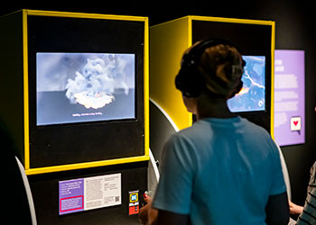 A silhouette of an adult playing The Longest Walk video game in the Game On exhibition at the National Museum of Scotland.