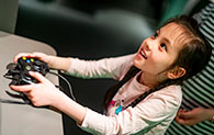 A child holding a gaming controller in the Game On exhibition at the National Museum of Scotland.