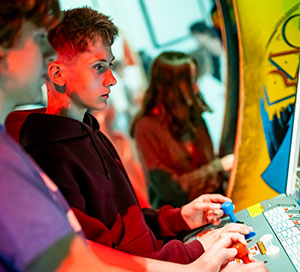 Two teenagers play an arcade game in the Game On exhibition at the National Museum of Scotland.