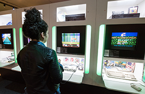 A visitor looking at gaming screens and hardware in the Game On exhibition at the Bienal de São Paulo