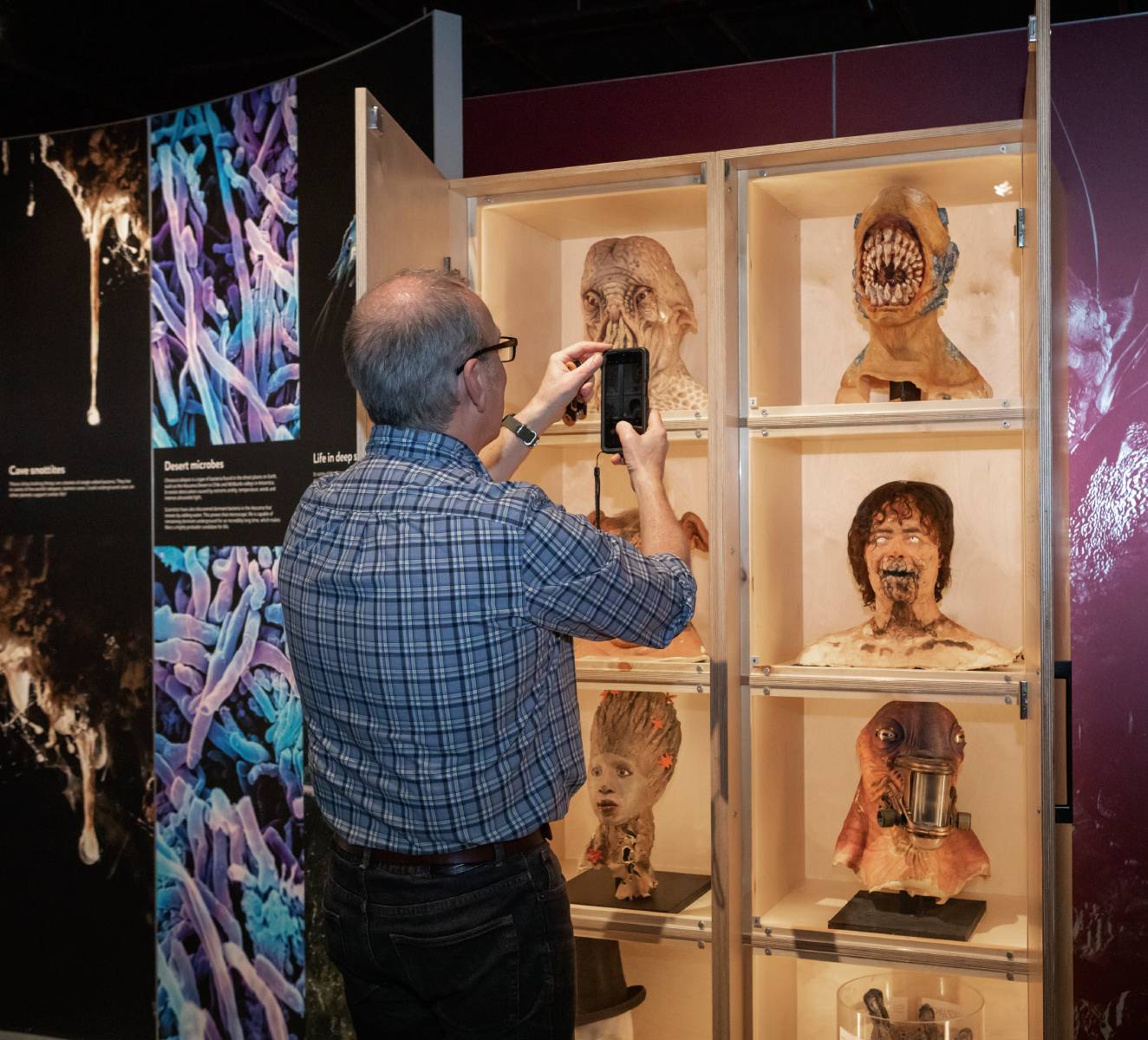 A man takes a photo on his phone of alien heads and props from the television series, Doctor Who.