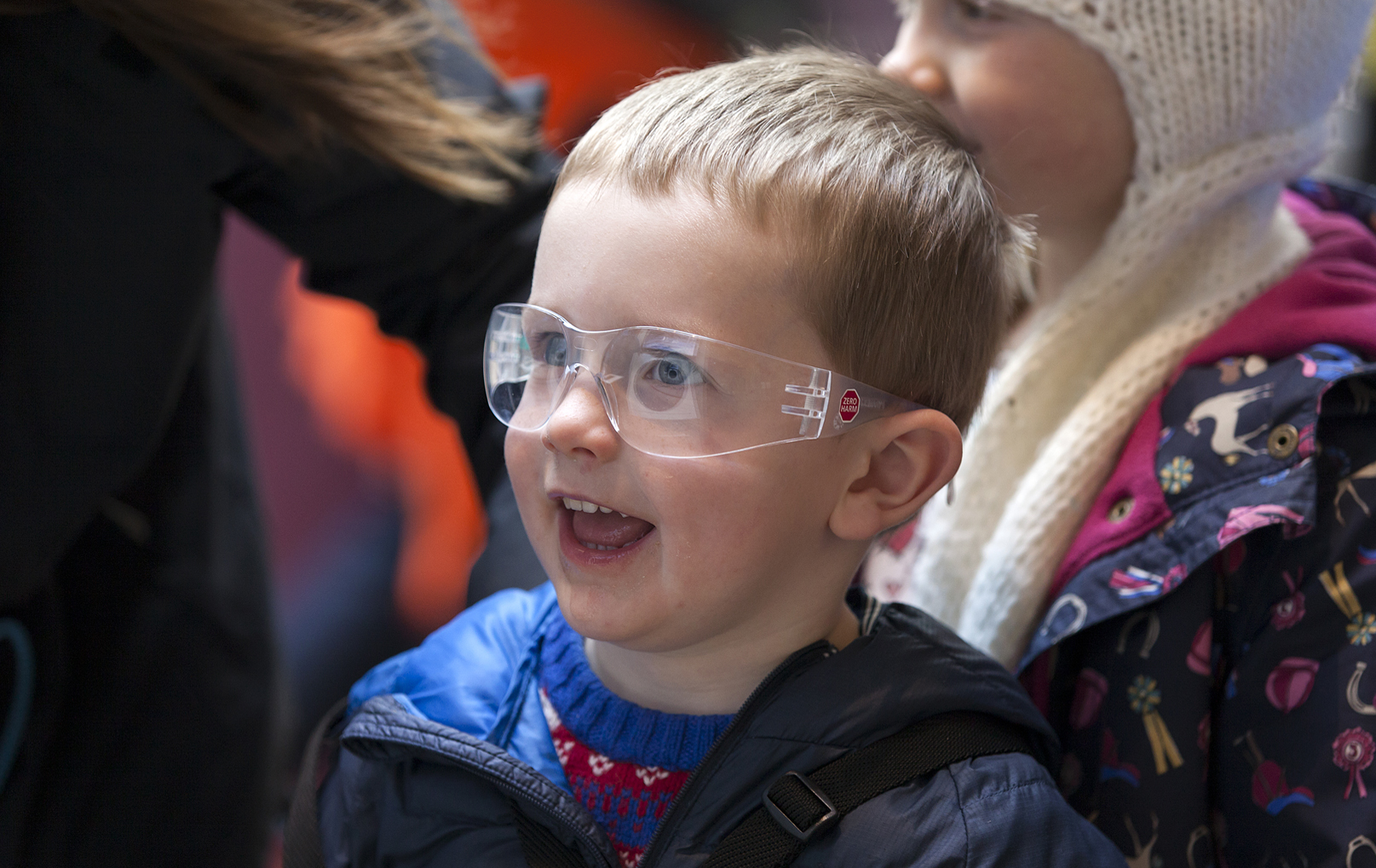 A young boy smiles while wearing protective googles during science activities. 