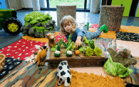 A young child plays with farm themed toys 