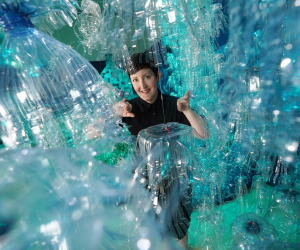 Dri Ali Clark peaks through the George Nuku artwork made of plastic bottles. 