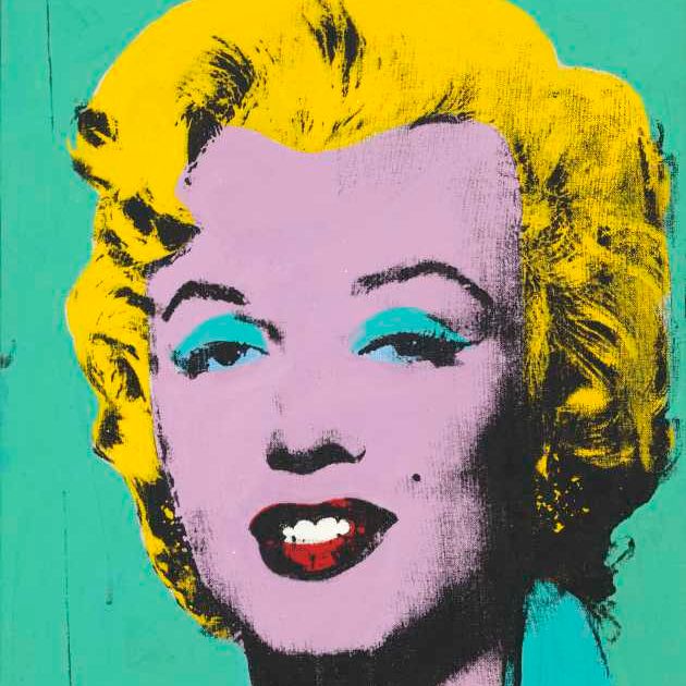 Ein Farbfoto von Marilyn Monroe in einem blauen Sommerkleid, wie sie vor einem bewaldeten Zaun steht, sie hält eine rosa Blume in der Hand. 