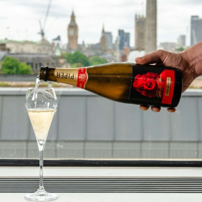 A bottle of champagne being poured into a glass, in the background is London skyline.