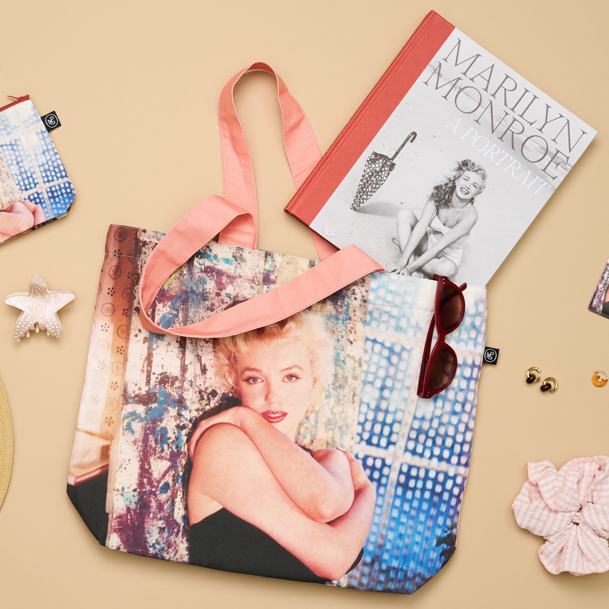 Ein Foto der Marilyn Monroe: A Portrait Ausstellungsreihe, darunter eine große Tasche, Sonnenbrille, Haargummi, Krallenklammer und Katalog.