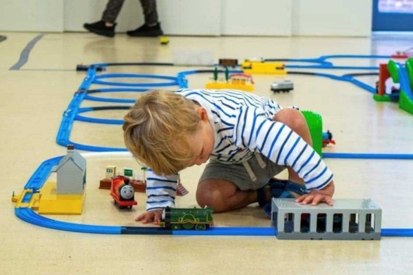 Young boy playing with trains on a track