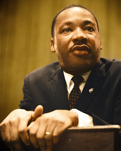 Dr. Martin Luther King in a suit, standing at a podium speaking