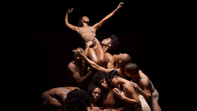 Alvin Ailey performers in tan outfits embrace eachother