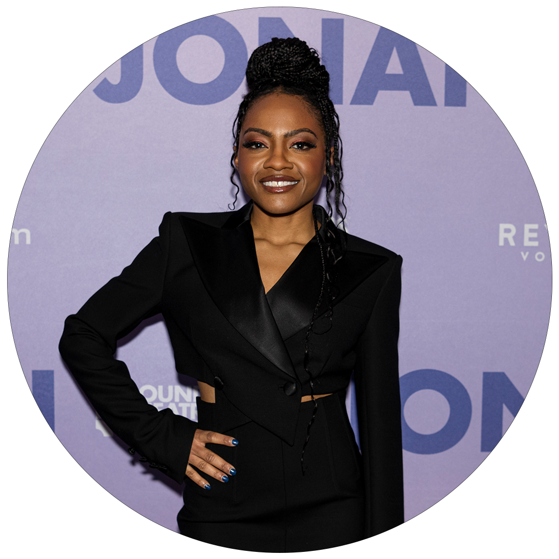 Gabby Beans smiling as she stands in front of a banner labeled, JONAH, during press day.