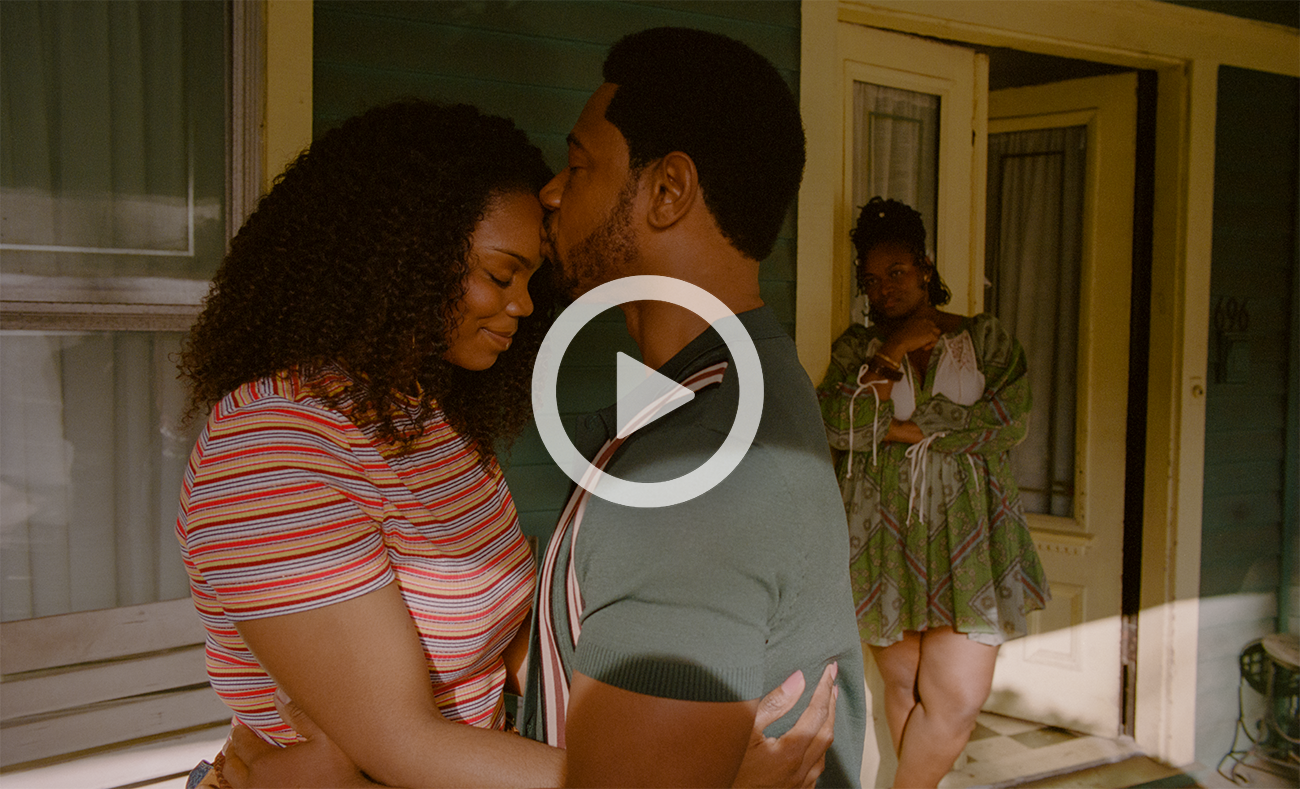 Brittany Inge being kissed on the forehead by Tory Kittles in front of a house as their characters. Stori Ayers, in character, looks the duo from the doorway.