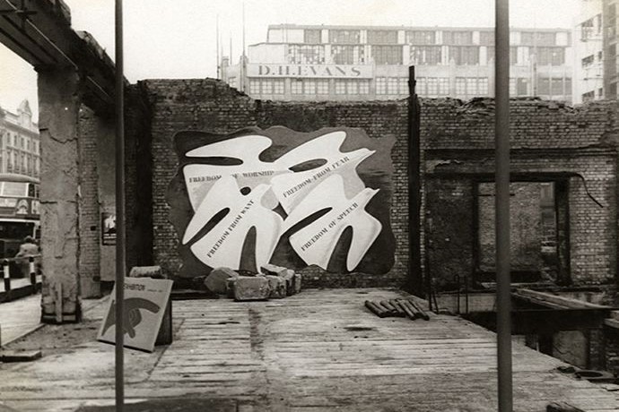 Four paper cutouts of doves against a destroyed brick facade. This image is in black and white.