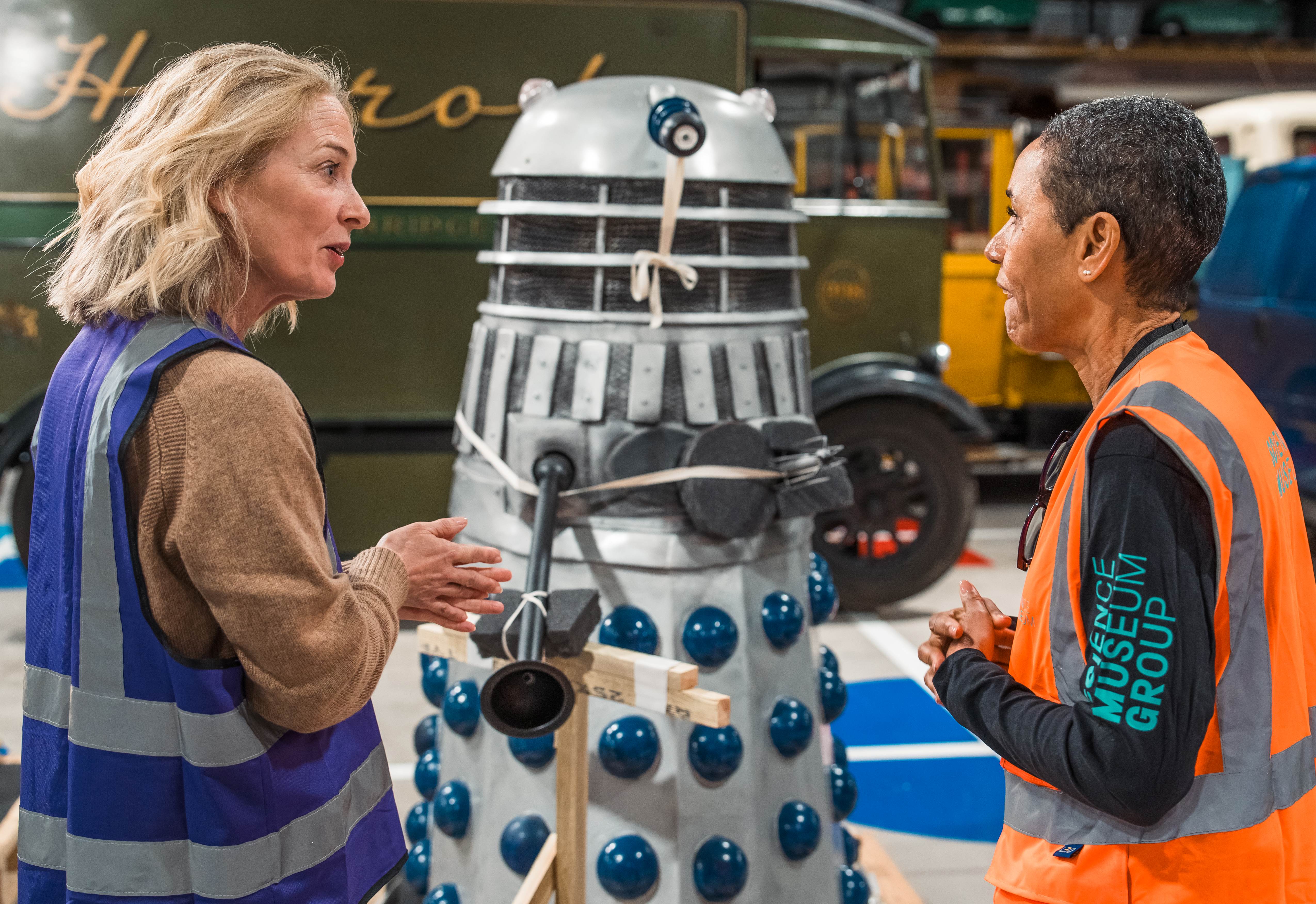A tour guide and visitor talking in front of the Dalek object on a behind-the-scenes tour.