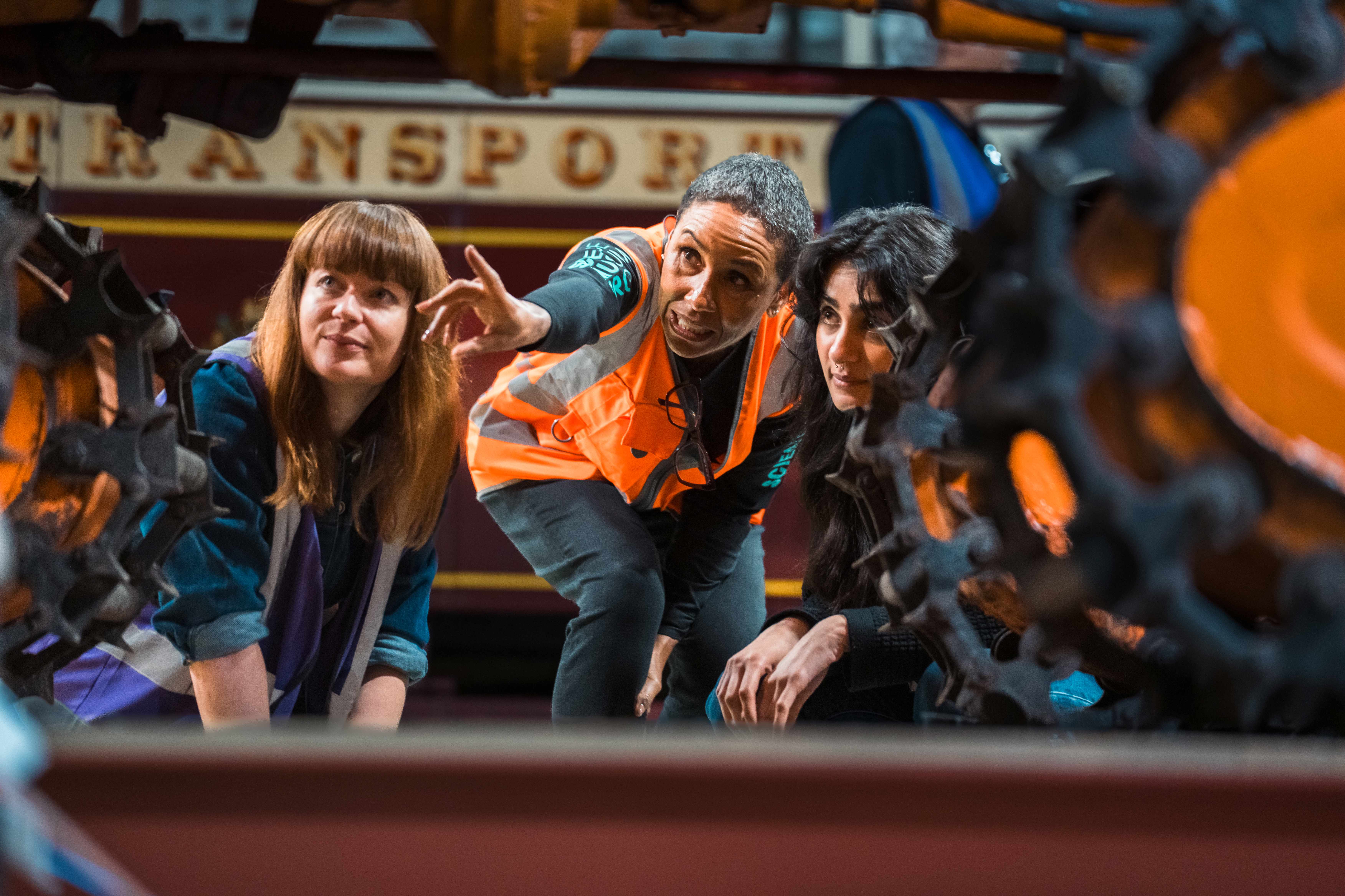 A tour guide and two visitors looking at the Sno-Cat vehicle on the behind-the-scenes tour.