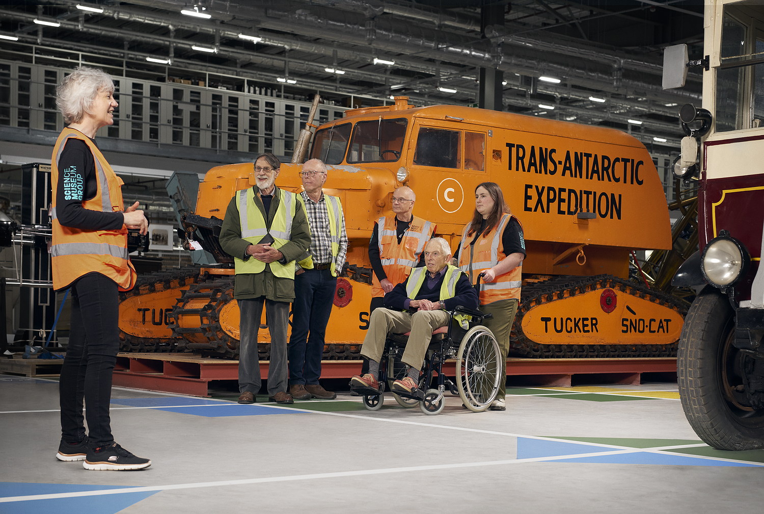 A tour guide talking about the Sno-Cat vehicle in front of a group of visitors.