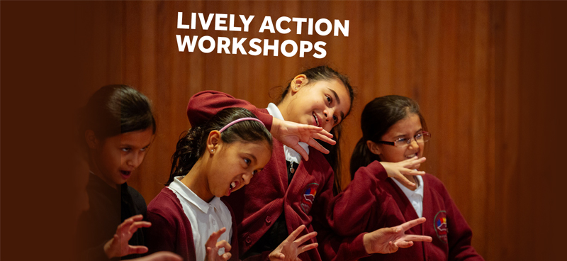 [IMAGE] Four school children pull faces and put their hands up in a Lively Action workshop.