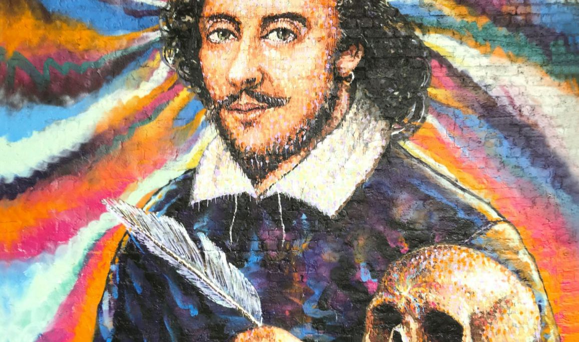 [Image] A photo of Jimmy C's multi-coloured street mural of William Shakespeare on Clink Street. He is holding a quill and a skull.