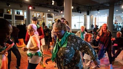A group of people of all ages are dancing and smiling in the Clore Ballroom mix an