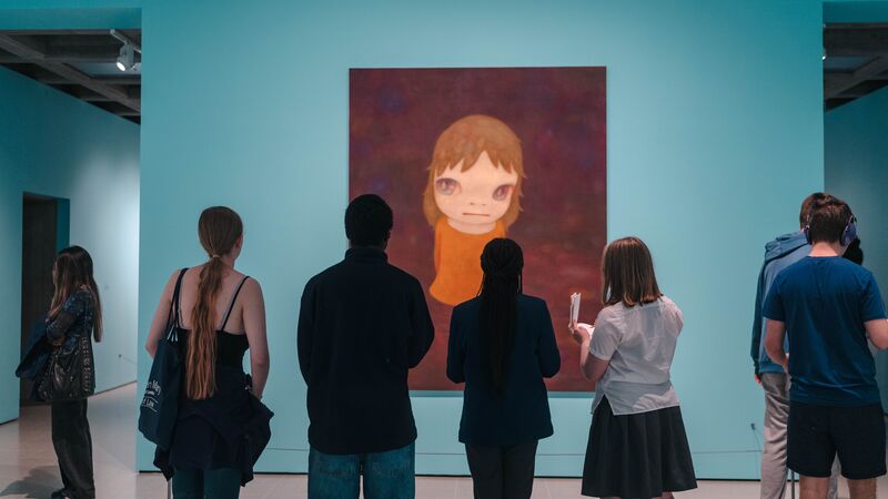 Excited children putting their hands up and smiling in an auditorium.