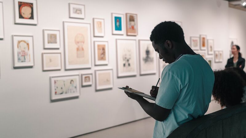 Excited children putting their hands up and smiling in an auditorium.