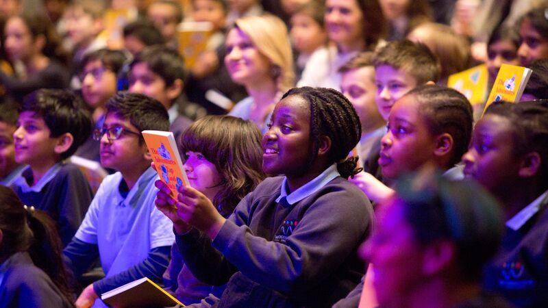 A student in the crowd lifting a book and smiling