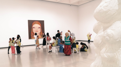 A group of teachers and teachers sat on and around a bench seat inside the Hayward Gallery