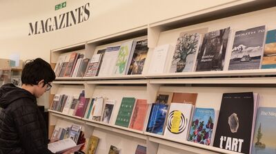 A young male student stood in front of a shelf with books on inside the National Poetry Library