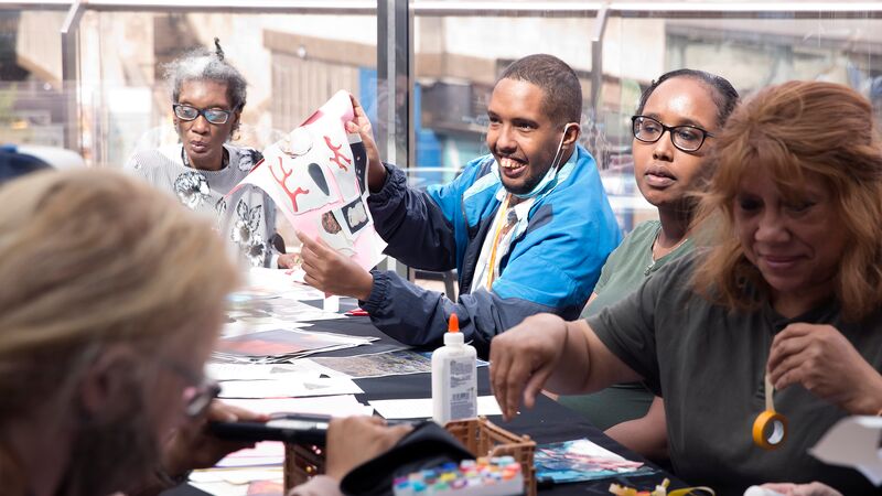A group of people sat around a table doing arts and crafts