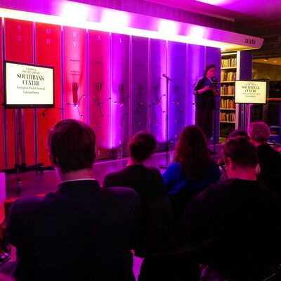 A person stood in front of a small crowd within the National Poetry Library